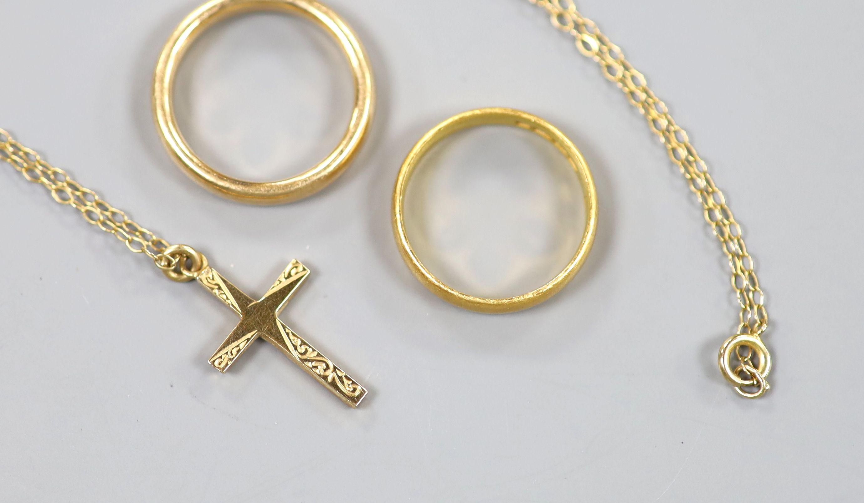 A 22ct god wedding band, 3.7 grams, a yellow meta wedding band, 5 grams and a modern 9ct gold cross pendant on a fine link chain, gross 2.1 grams.